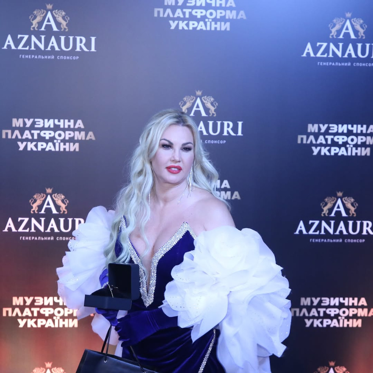 Співачка Камалія позує на хіднику у чорній сукні і білій накидці